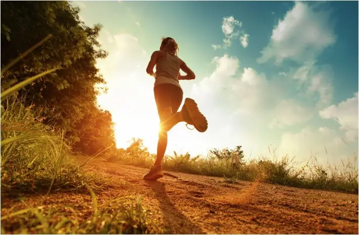 Runner on dirt trail with sunshine